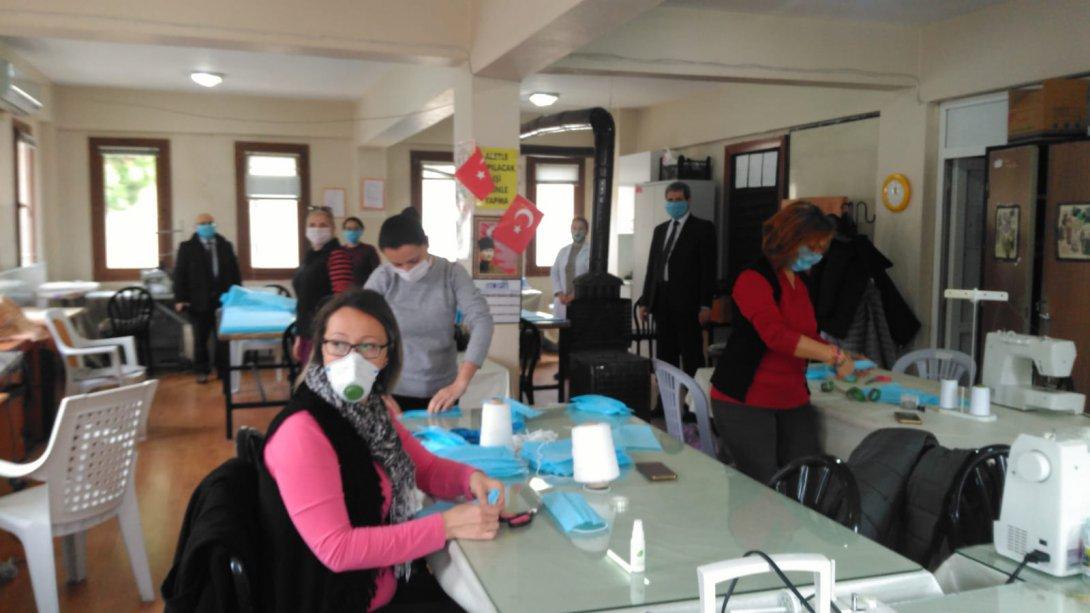  Foça Halk Eğitimi Merkezinde gönüllü öğretmen, usta öğretici ve kursiyerlerden oluşan ekip maske dikimi yapmaktadır.